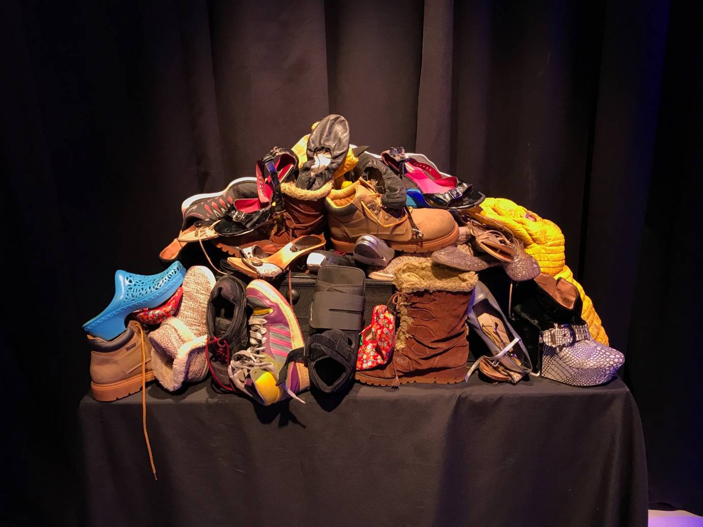A pile of shoes on a black suitcase